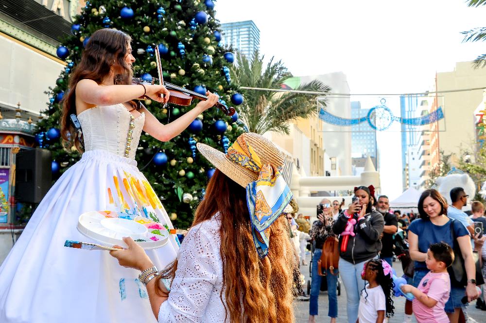 women playing violin while another woman paints her dress